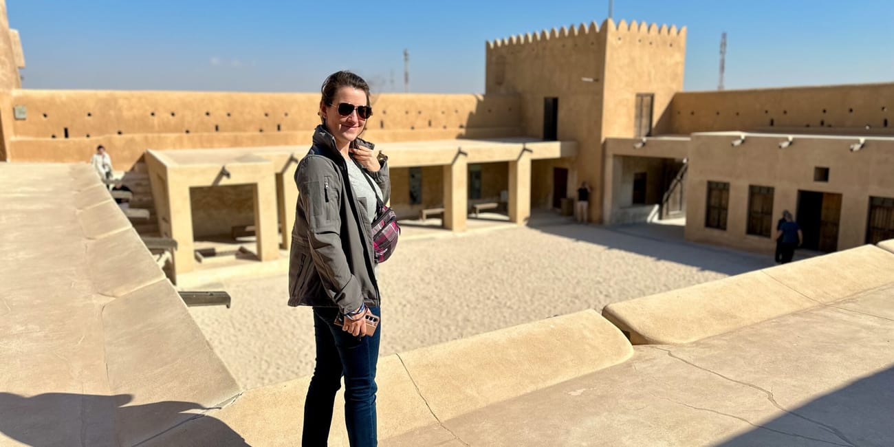 Kobieta w al zubara fort w dosze, stojąca na dziedzińcu pod flagą kataru.