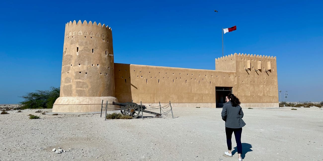 Fort al zubara w doha w katarze z flagą na wieży i osobą idącą przed wejściem