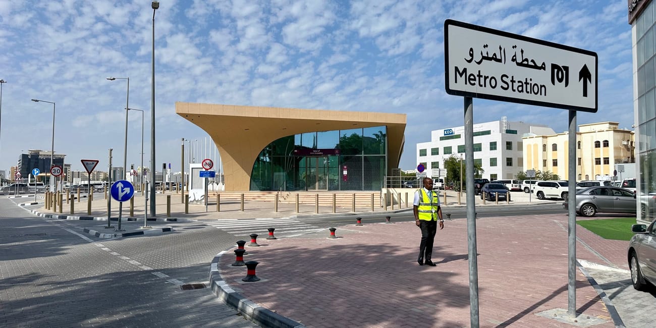 Wejście do stacji doha metro w ad-dausze z drogowskazem i ochroniarzem.