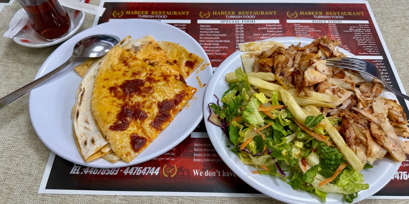 Posiłek w habeeb restaurant w doha foods w katarze: tortilla z serem oraz talerz z kurczakiem, frytkami i sałatą.