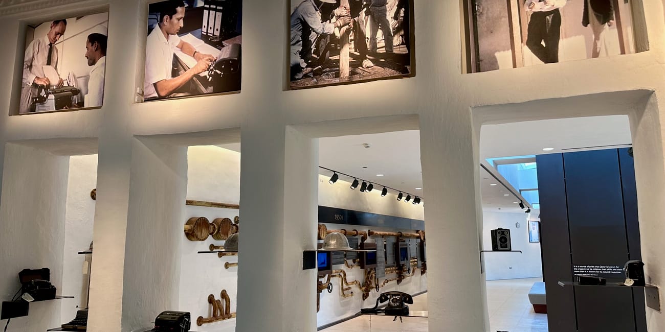 Wystawa historyczna w doha company house z archiwalnymi zdjęciami i dawnymi urządzeniami biurowymi.