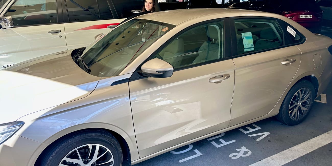 Beżowy sedan na parkingu w doha, katar, przy stanowisku rent a car.