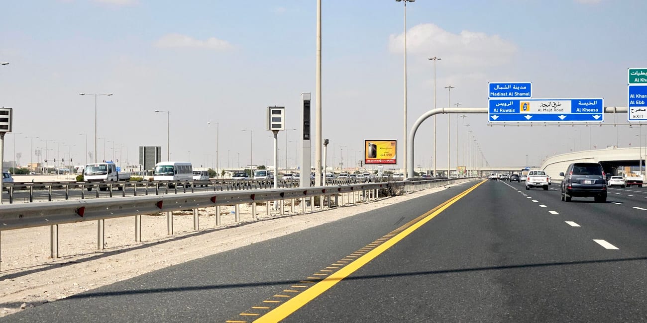 Autostrada w doha, katar, z oznakowaniem kierunkowym i ruchem pojazdów pod pochmurnym niebem