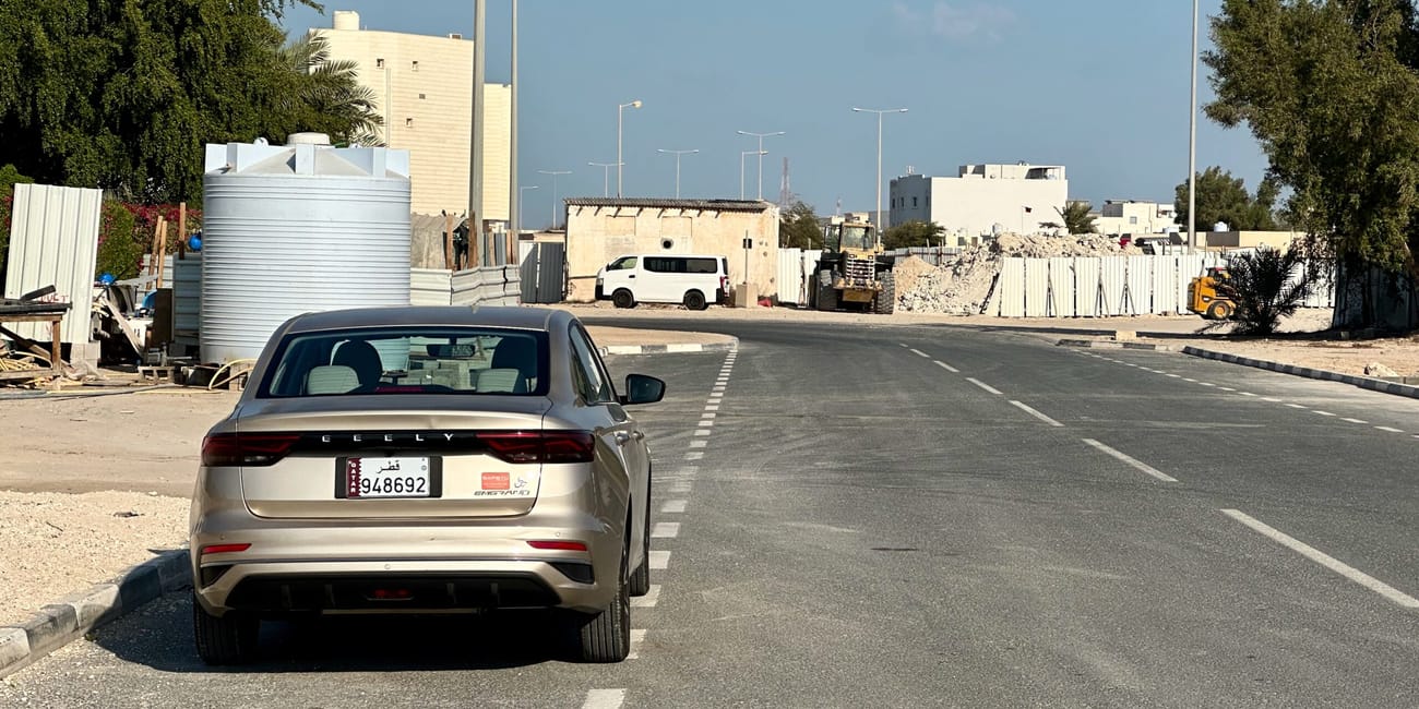 Droga w doha, katar, z zaparkowanym samochodem i trwającymi pracami budowlanymi po bokach