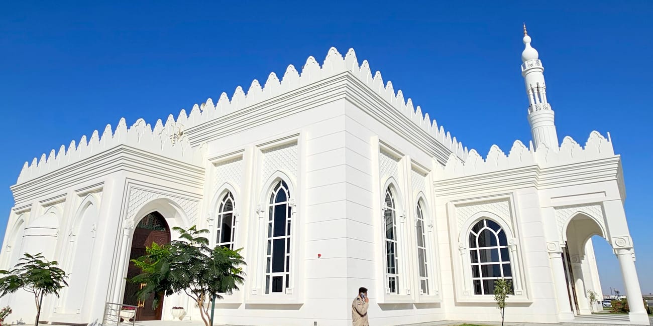 Meczet al sayedah khadeeja w abu zabi z białą fasadą i minaretem pod błękitnym niebem