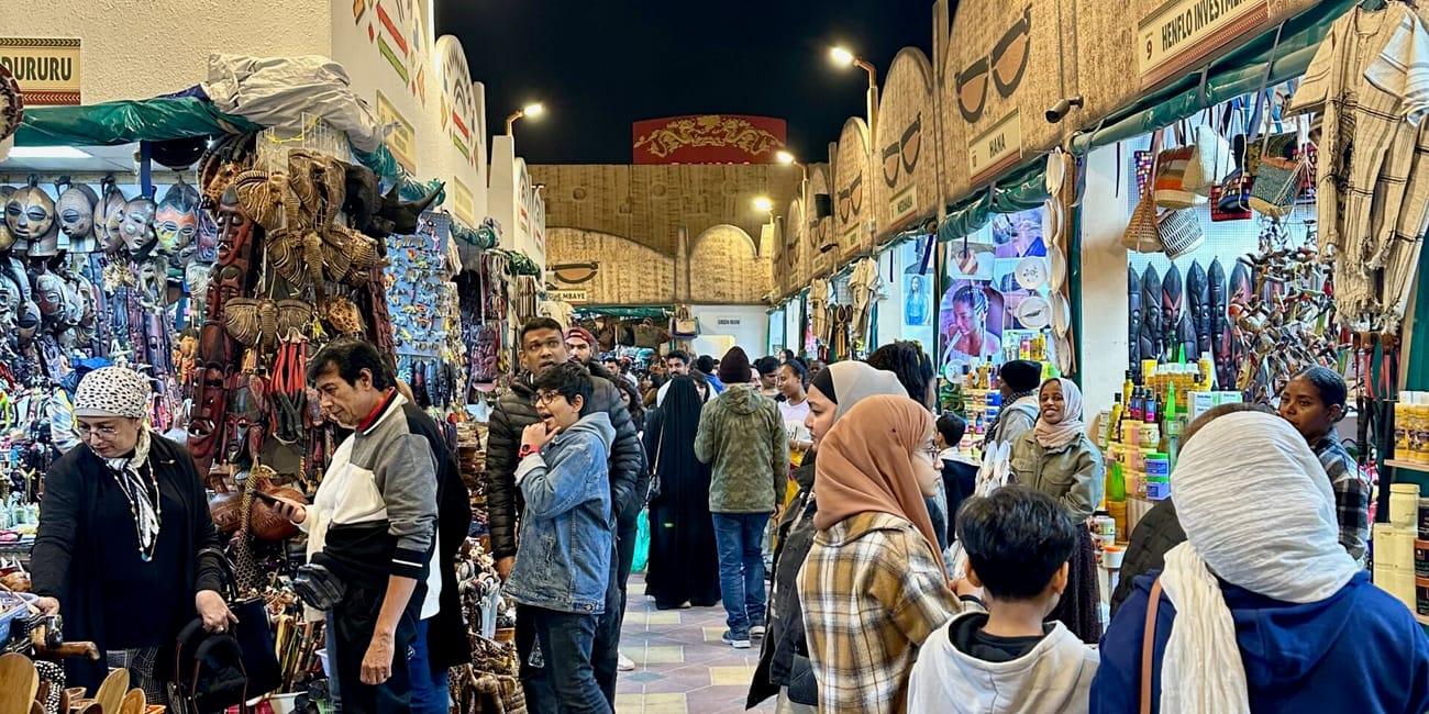Dubai global village nocą, tłoczny targ z pamiątkami i stoiskami pełnymi rękodzieła.