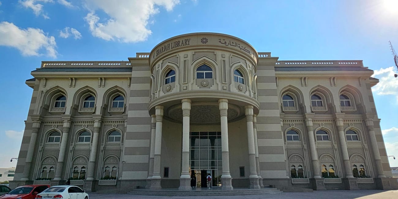 Sharjah library w szardży, okazały budynek z arkadową fasadą pod błękitnym niebem.