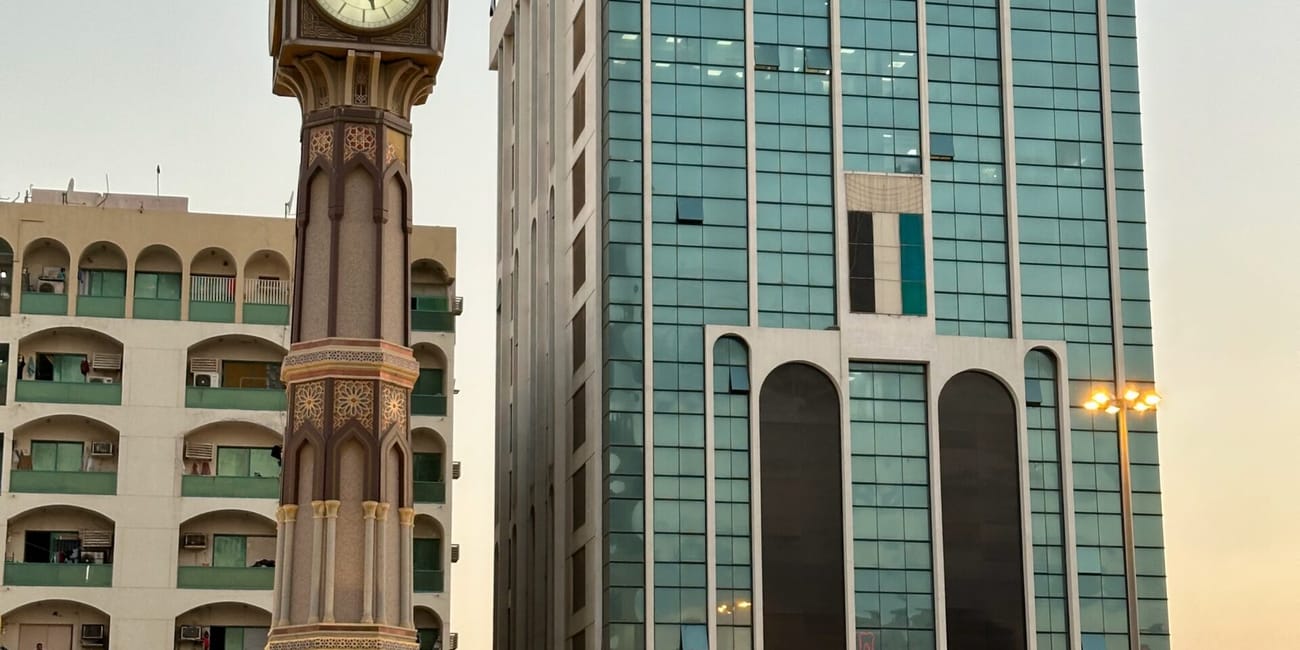 Sharjah clock tower z fontanną i budynkiem biurowym w tle, uae.