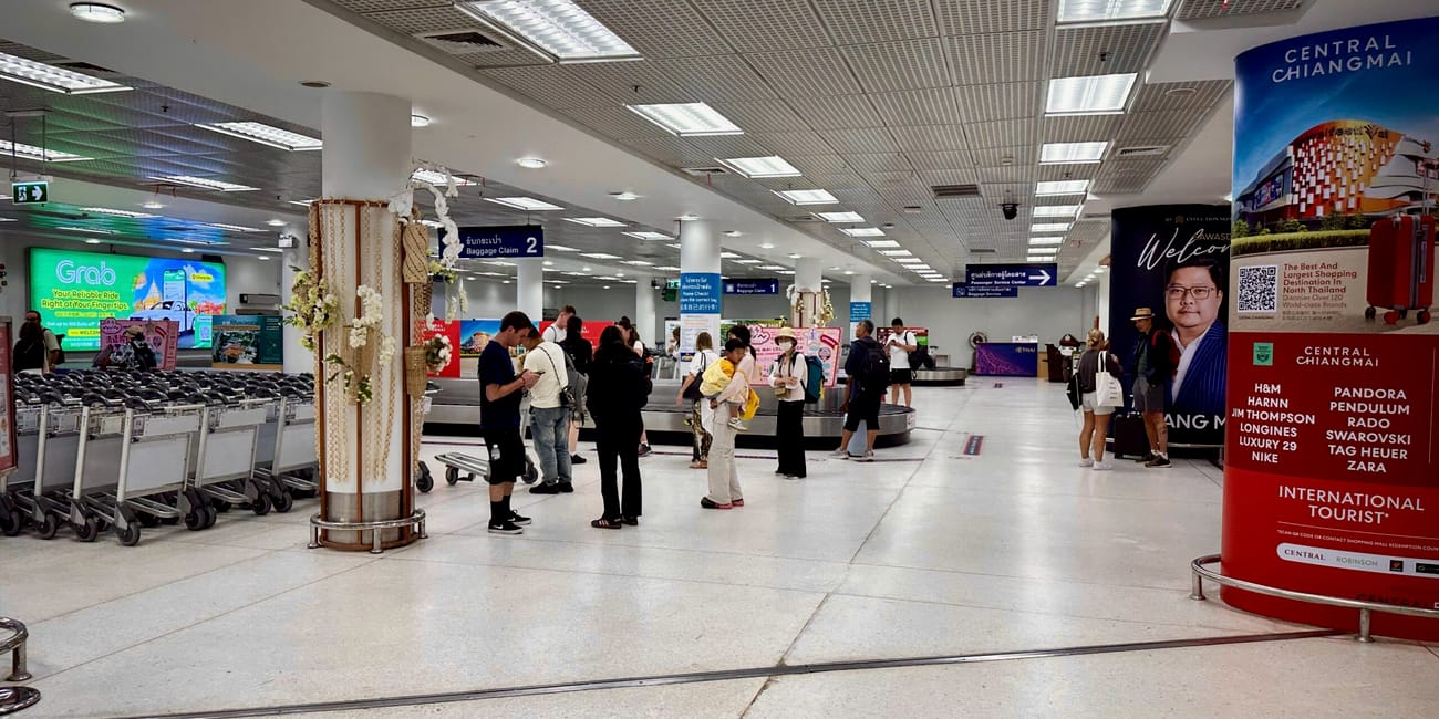 Bagażownia na lotnisku w chiang mai, z podróżnymi i wózkami bagażowymi