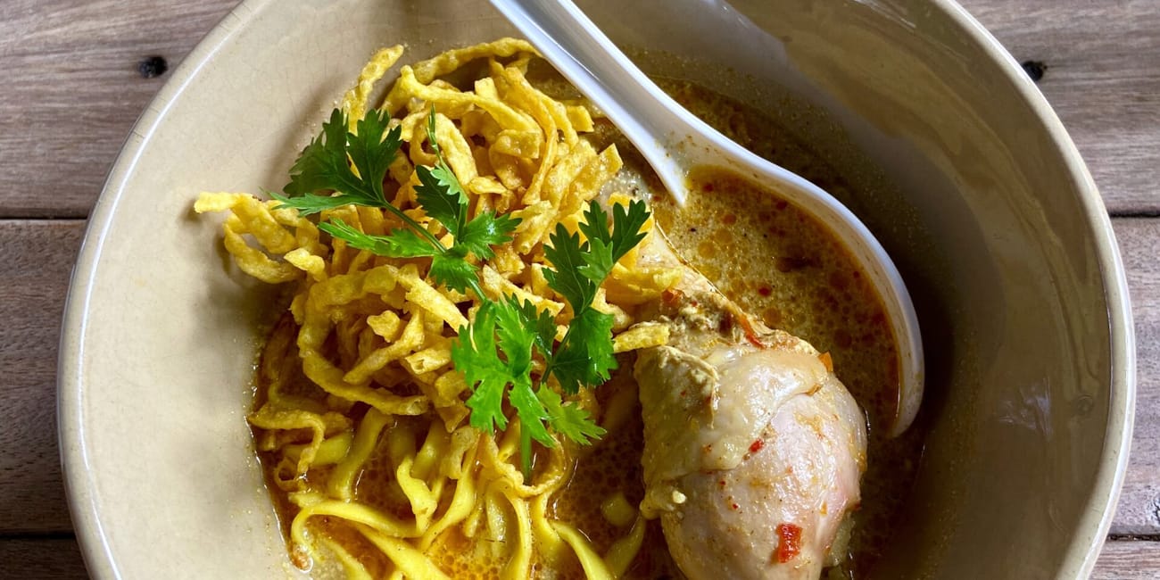 Chiang mai foods w tajlandii: miska curry z kurczakiem, makaronem i chrupiącymi dodatkami.
