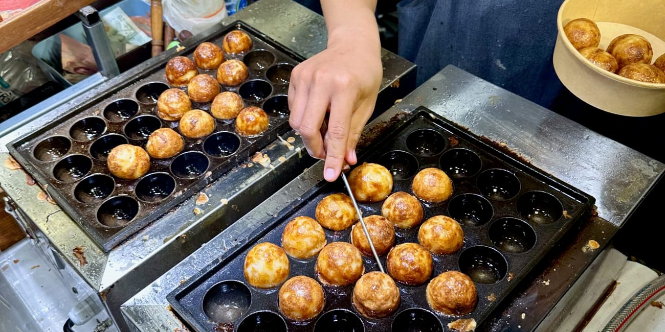 Stoisko z takoyaki w one nimman w chiang mai, thailand, z kuleczkami smażonymi na płycie.