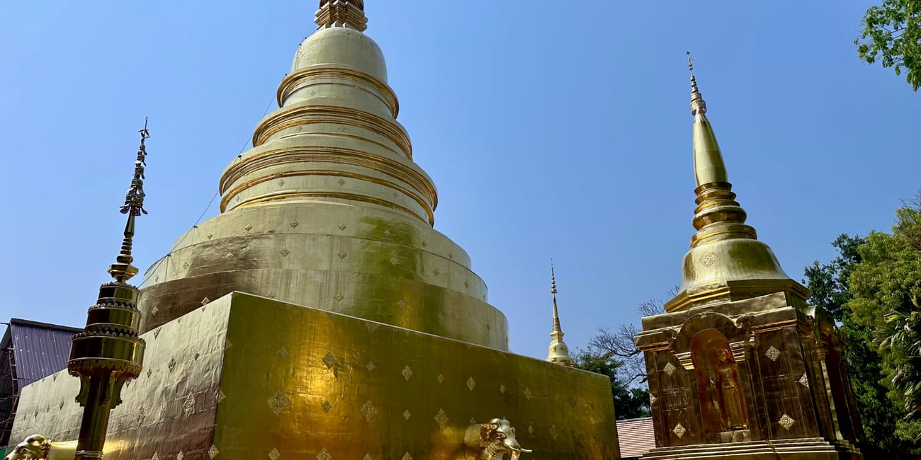 Wat phra singh woramahawihan w chiang mai z dużą złotą stupą pod błękitnym niebem