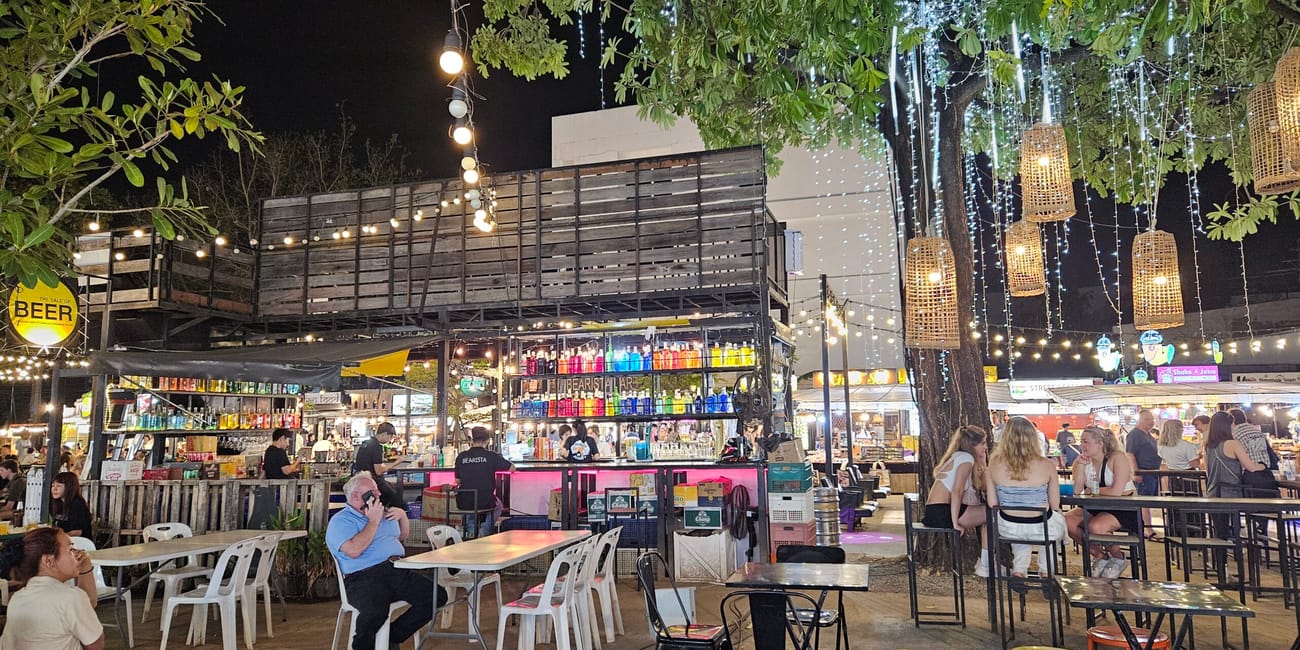 Chiang mai night bazaar nocą, z ogródkami barowymi, stolikami i światełkami pod drzewami