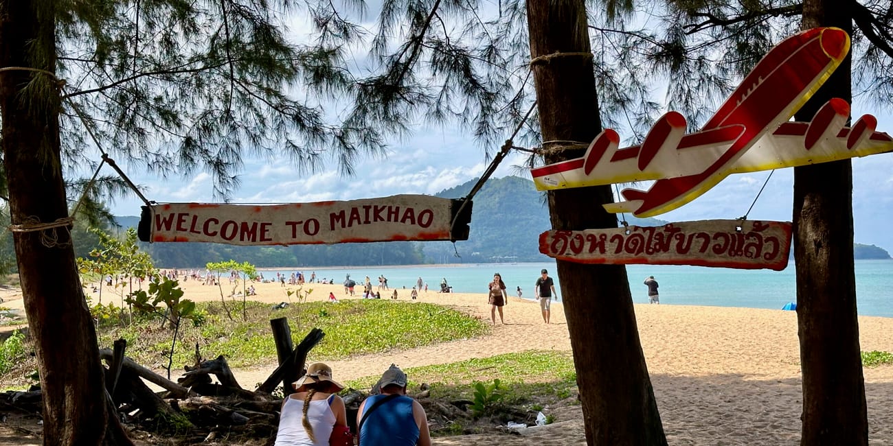 Plaża mai khao na phuket w tajlandii z napisem welcome to maikhao i turystami na piasku