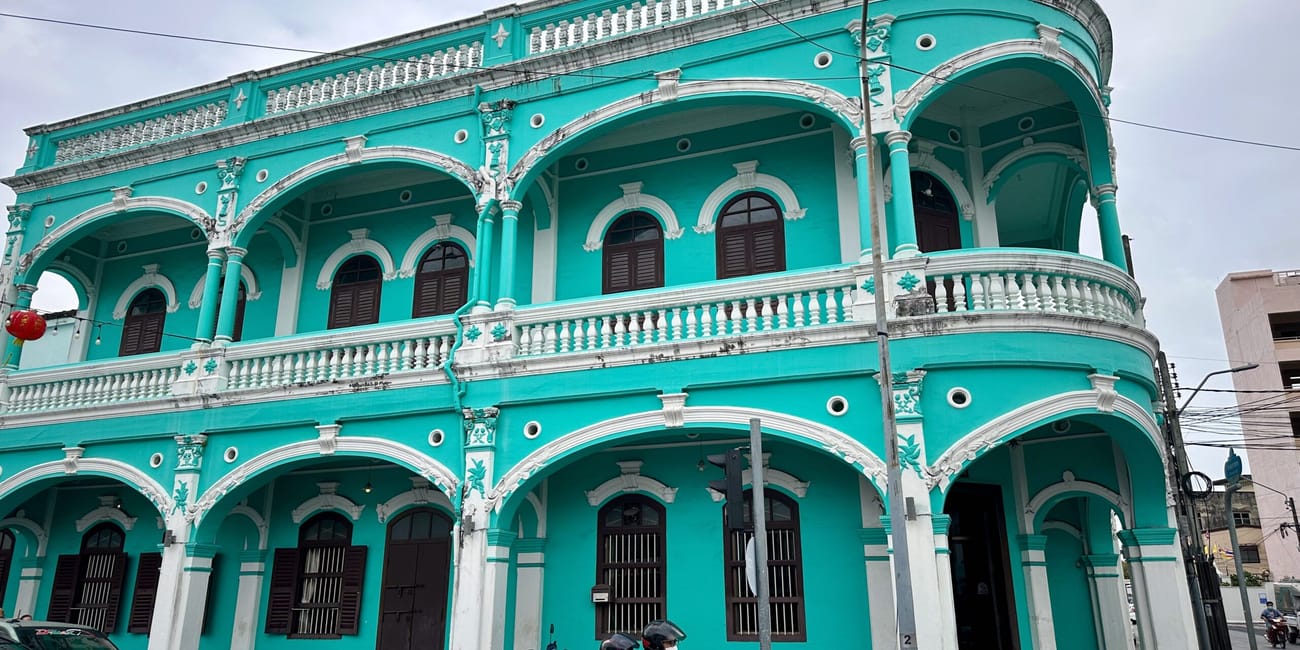 Błękitno-turkusowa zabytkowa kamienica w phuket old town, z arkadami i balkonami.