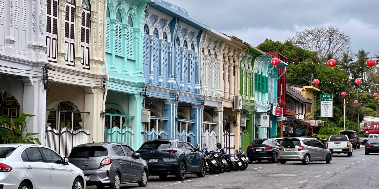 Kolorowe kolonialne kamienice w phuket old town z zaparkowanymi samochodami i czerwonymi lampionami