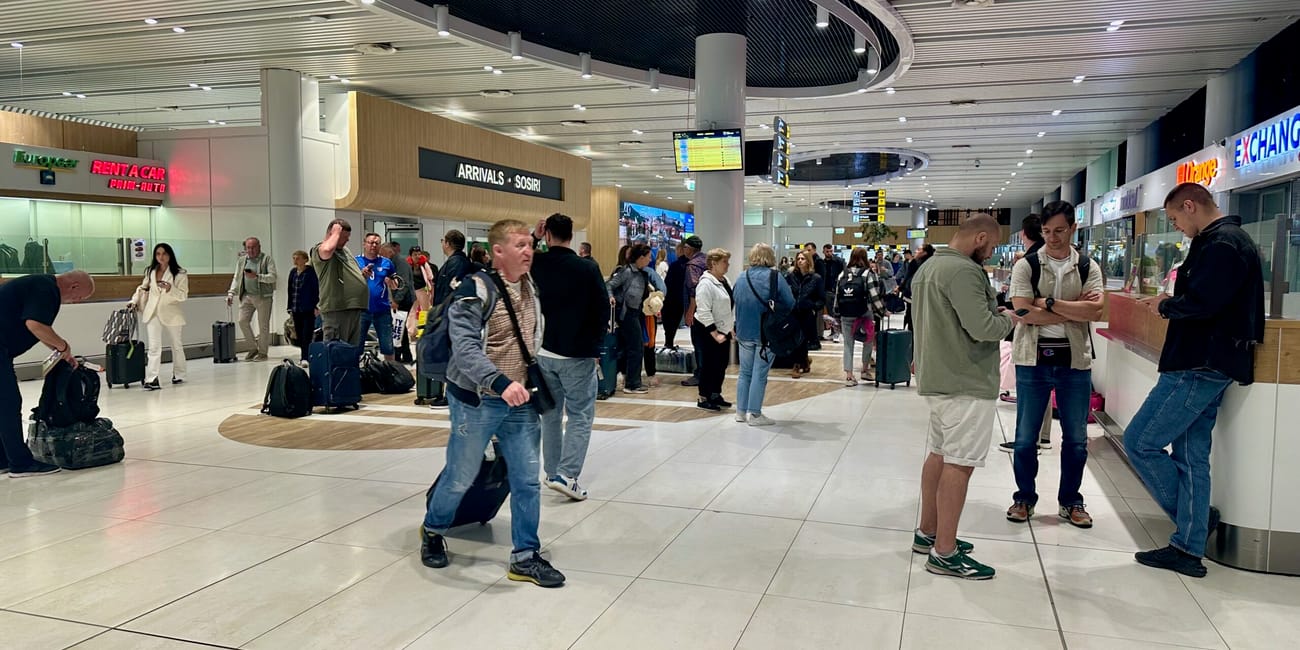 Chisinau airport arrivals hall with travelers waiting under arched ceiling and overhead flight boards