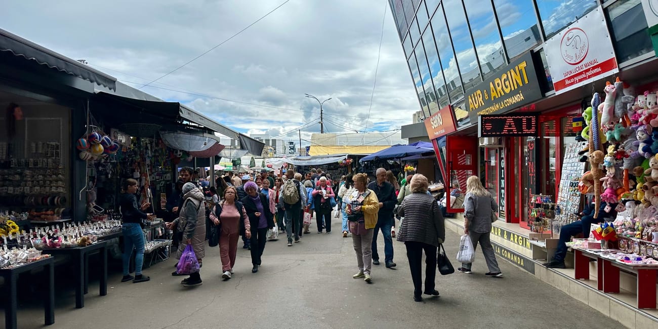 Crowded market street in chisinau, moldova, with shops, stalls, and colorful souvenirs under cloudy skies