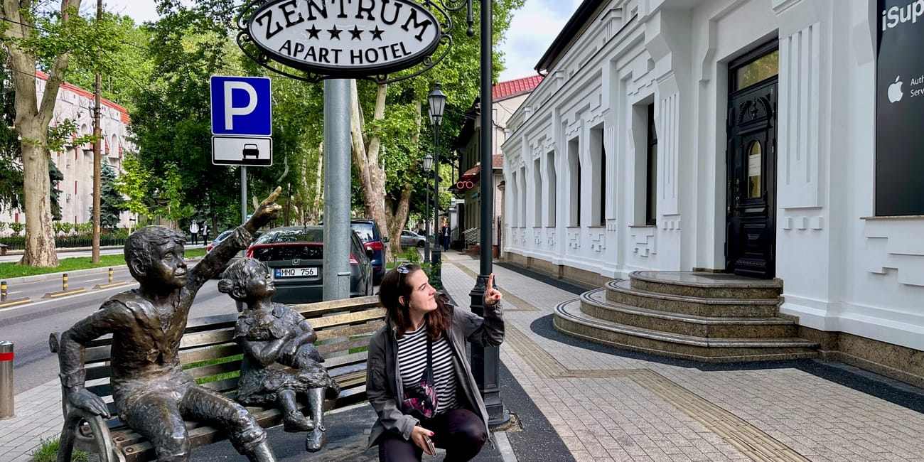 Chisinau, moldova city street with a bronze statue and an off-white hotel entrance sign reading zentrum apartment hotel