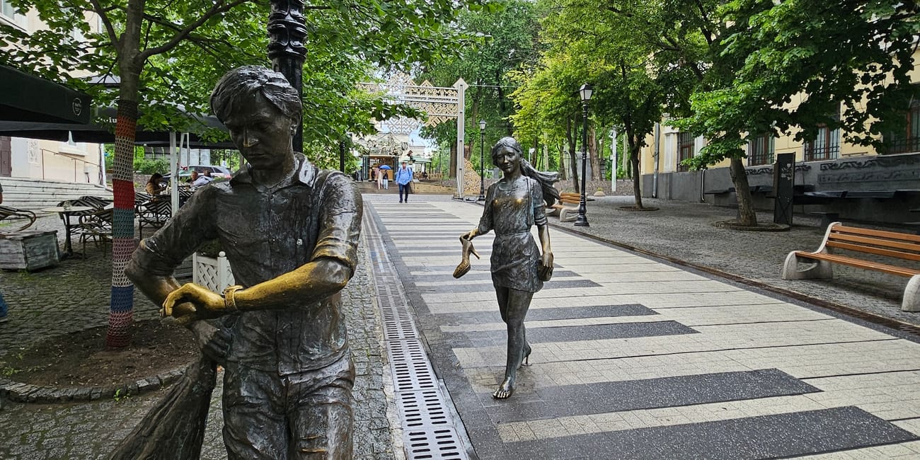 Eugen doga street w kiszyniowie z brązowymi figurami spacerujących dzieci i zielonymi drzewami wypisanymi na deptaku
