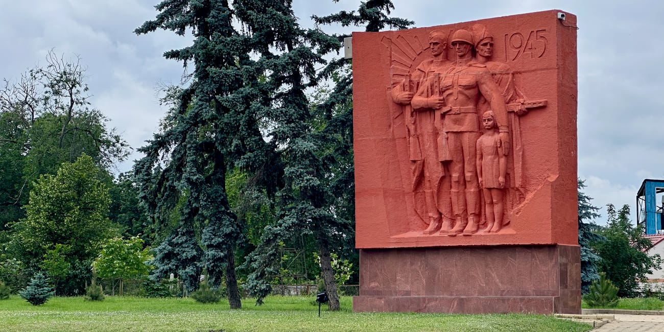 Chișinău eternity memorial complex: czerwony pomnik z reliefem żołnierzy i datą 1945 wśród drzew.