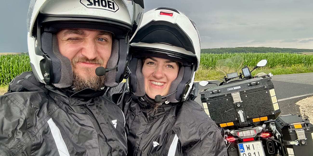 Jadzia i filip w kaskach pozują przy motocyklu na wiejskiej drodze pod warszawą.