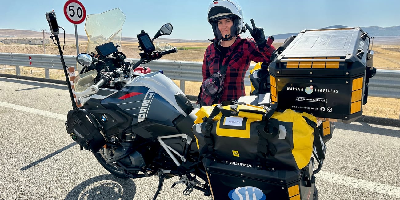Motorcyclist wearing a helmet and gloves poses with touring bikes on a road near göreme, turkey for desert horizons motorcycle expedition