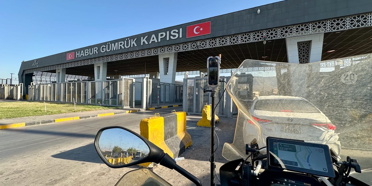 Desert horizons motorcycle expedition at the turkey border customs checkpoint, with motorcycle dashboard and entry barriers