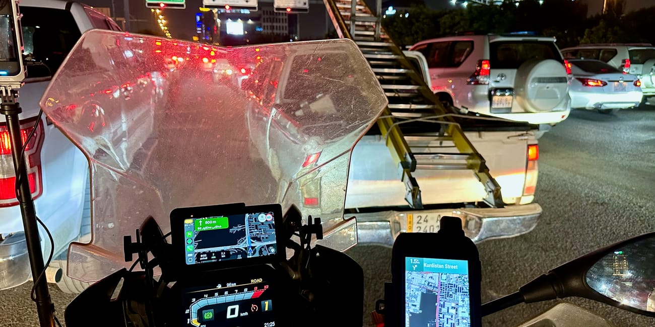 Nocny postój motocykla z nawigacją na kurdistan street w kurdistanie, w korku obok samochodów.