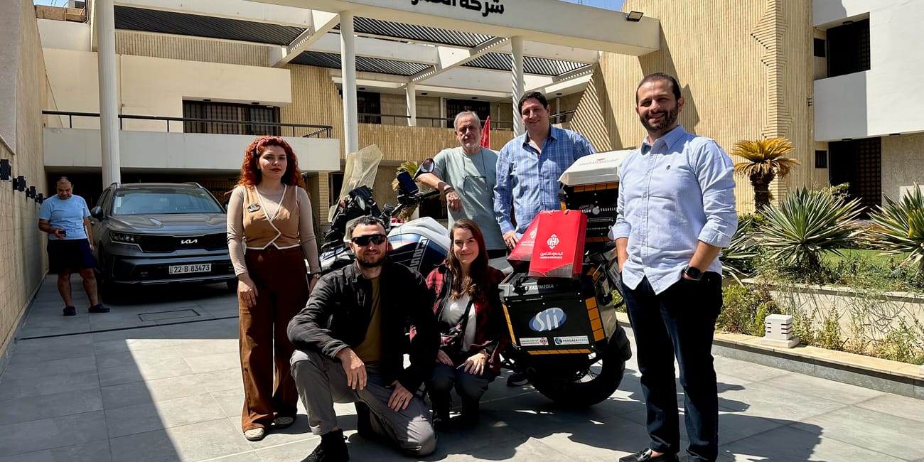 Grupa osób przy motocyklu przed budynkiem firmy al hamra w bagdadzie.