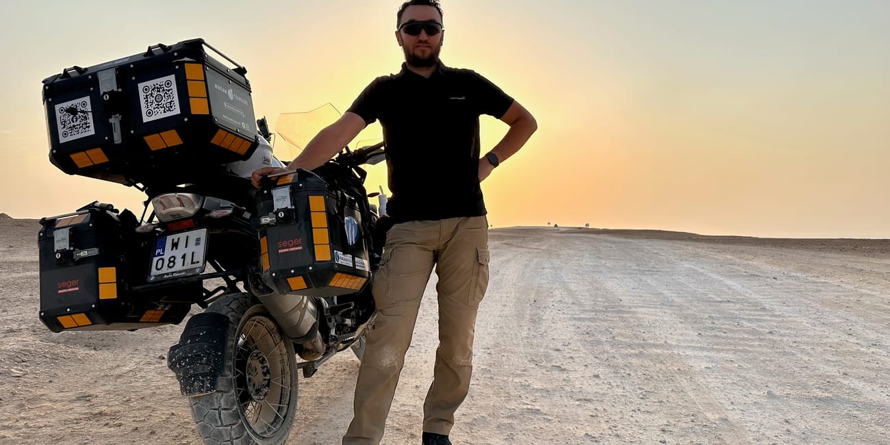 Motocyklista przy obładowanym motocyklu na pustynnym płaskowyżu edge of the world w arabii saudyjskiej.