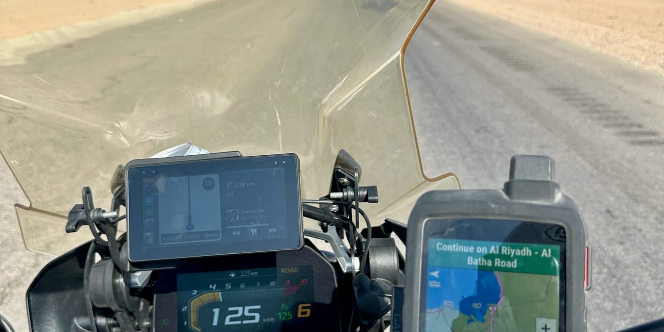 Motocykl na pustynnej drodze w arabii saudyjskiej, z nawigacją pokazującą trasę do al riyadh–al batha road.