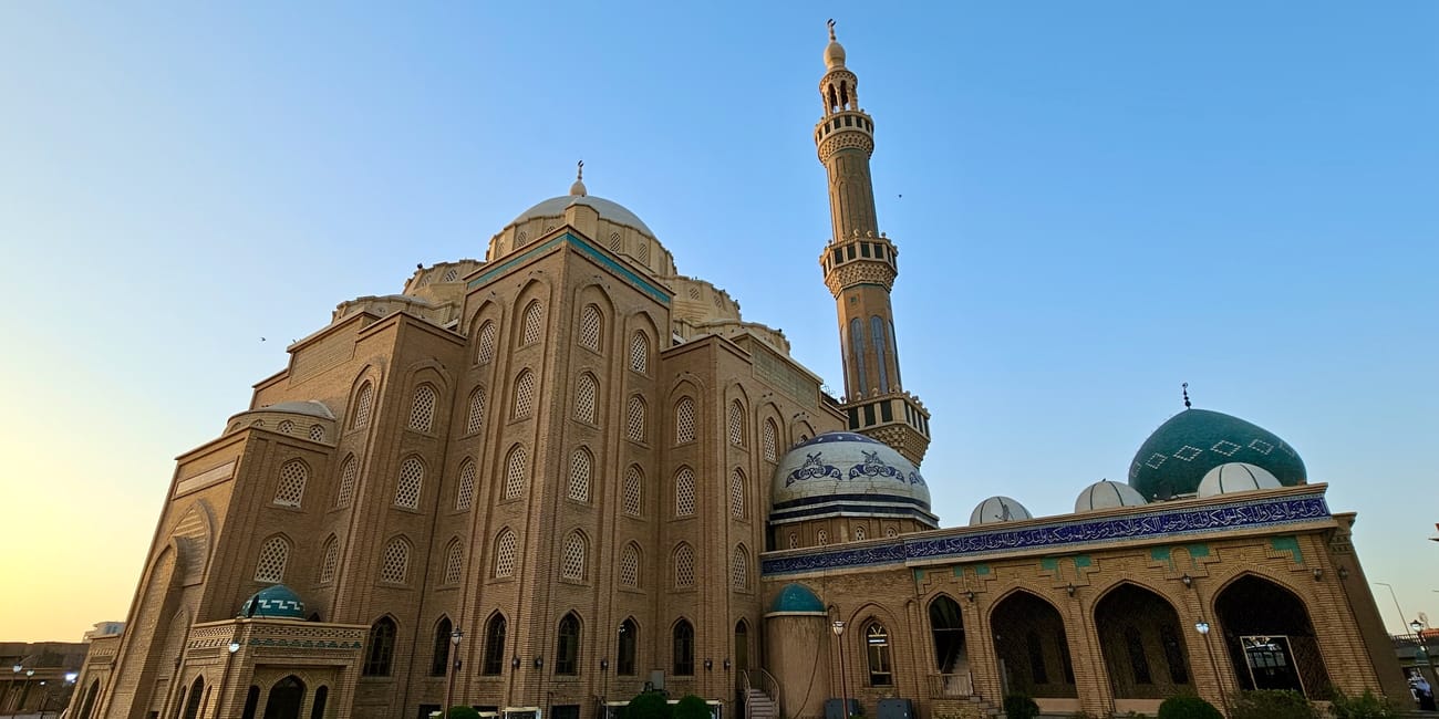 Meczet w erbilu z kopułami i wysokim minaretem o zmierzchu