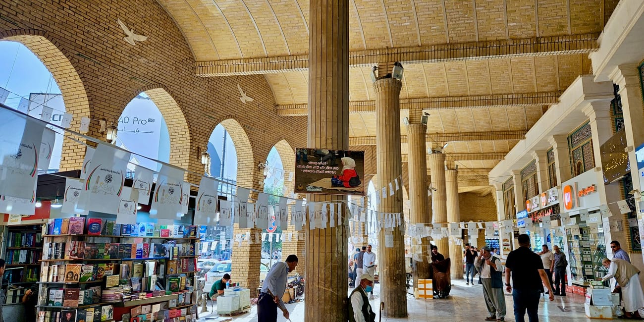 Kryty targ qaysari bazaar w erbilu z księgarniami i przechodniami.
