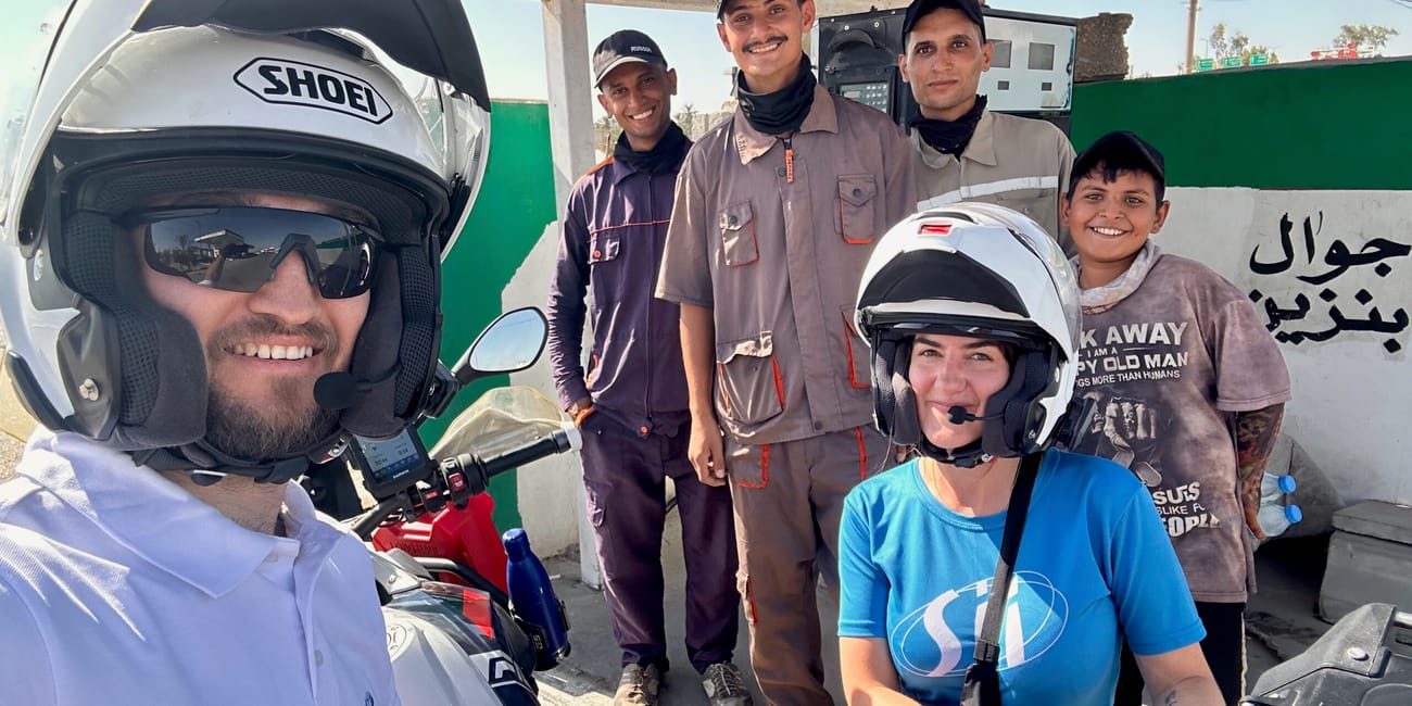 Ludzie pozują przy stacji benzynowej w bagdadzie, obok motocykli.