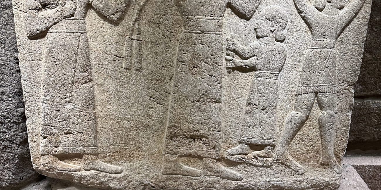 Stone relief at turkey’s ankara civilization museum showing figures in ceremonial procession and holding objects