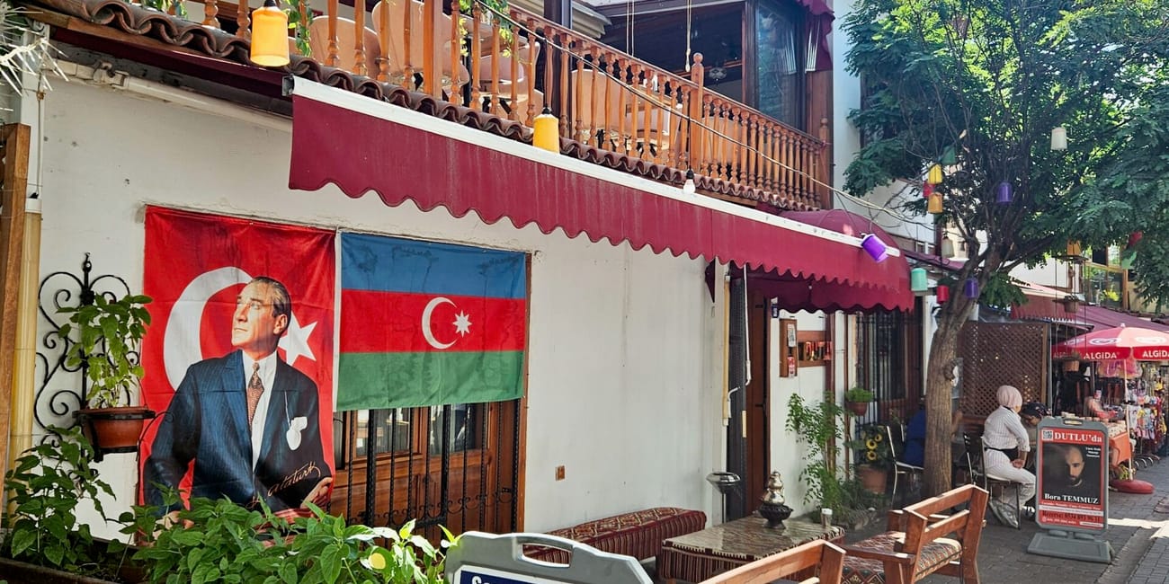Turkey, ankara historical houses street view with a turkish flag banner, café seating, and menu stand under trees