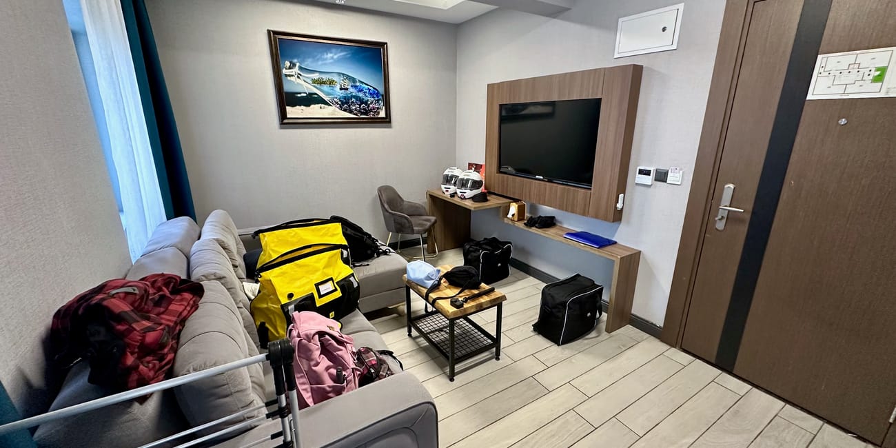 Pokój hotelowy w ankarze z rozrzuconymi bagażami i telewizorem na ścianie.