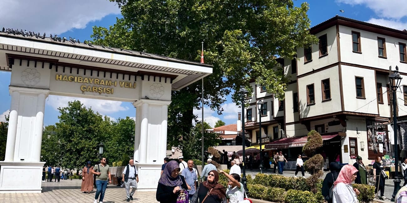 People walk in front of ankara mayram mosque entrance gate in ankara, turkey under a blue sky