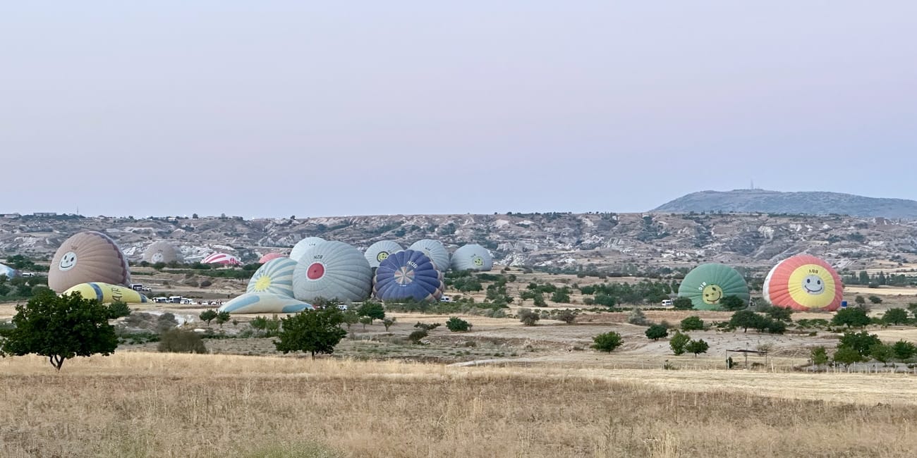Balony na ogrzane powietrze w goreme o poranku, rozłożone na polu przed startem