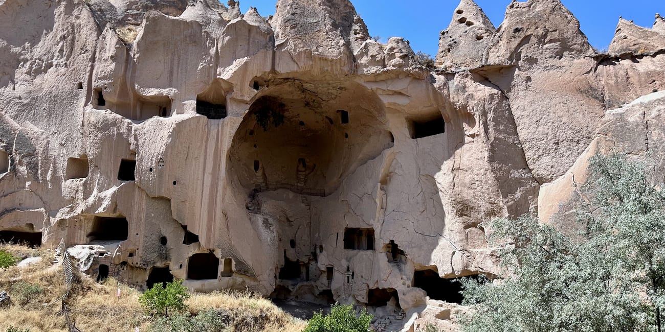 Goreme zelve museum w turcji: skalne formacje z wykutymi jaskiniami i otworami w ścianach.