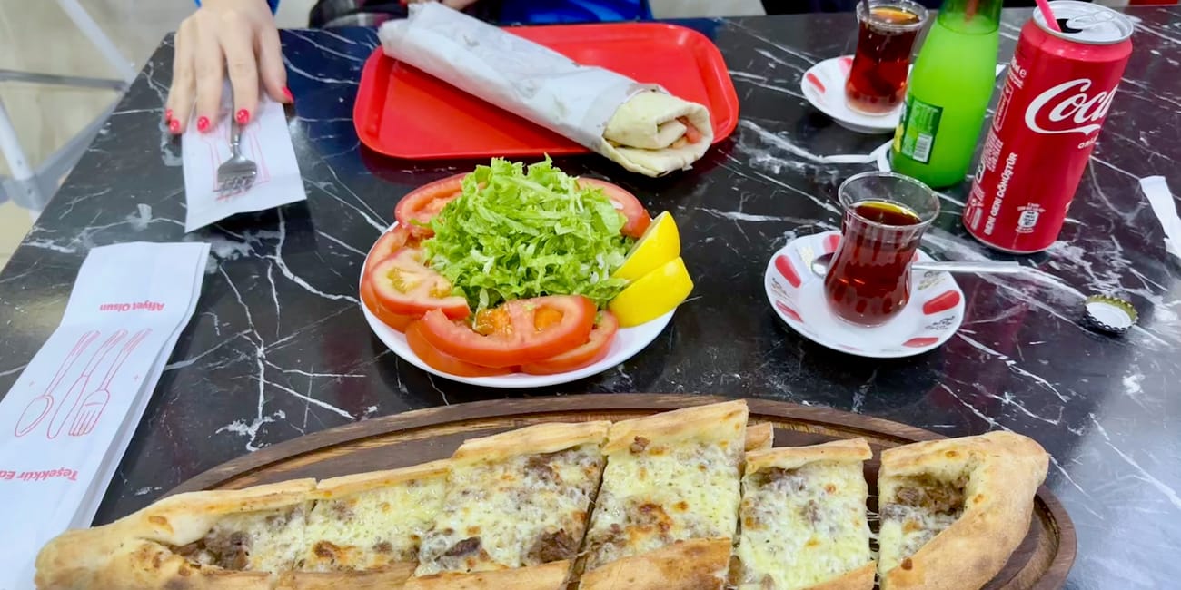 Stół z tureckim jedzeniem ulicznym w stambule: pide, sałatka i herbata.