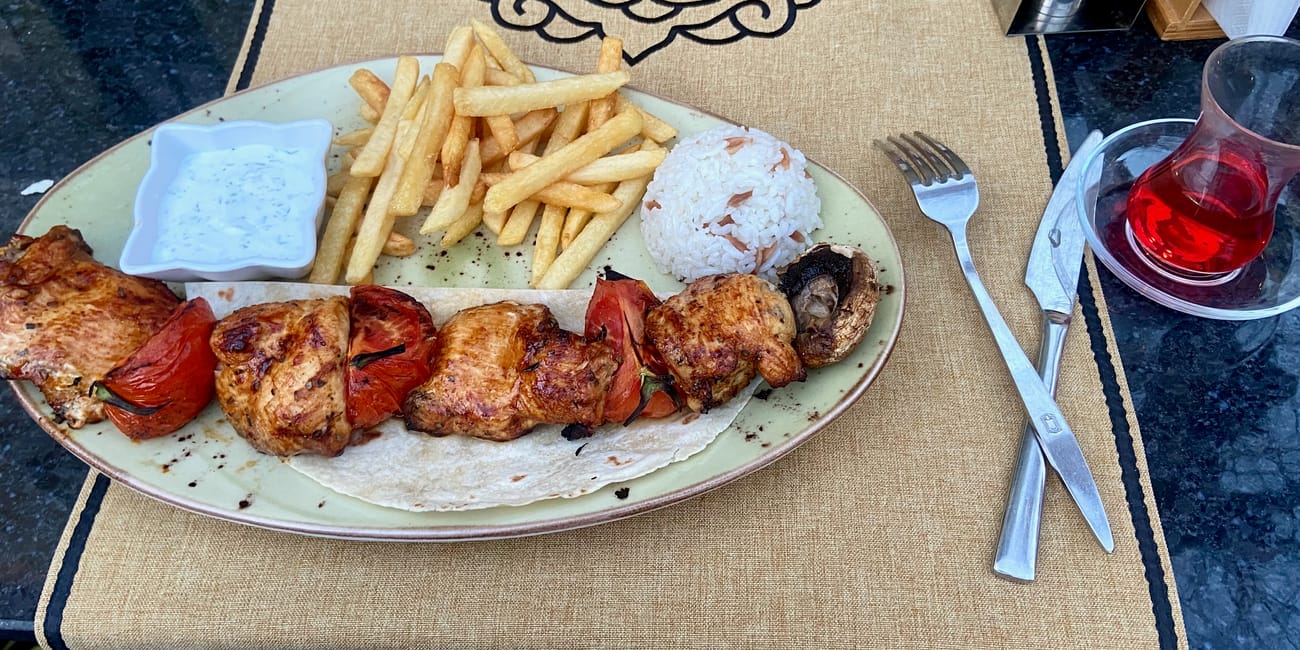 Szisz kebab z kurczakiem, frytkami, ryżem i sosem na talerzu w stambule