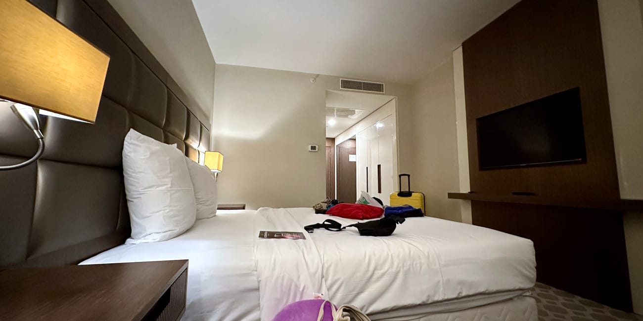 Pokój w hotelu mercure w stambule z dużym łóżkiem, telewizorem i walizką.