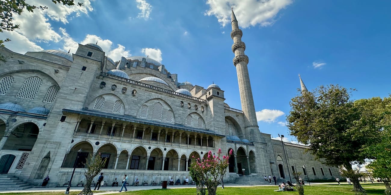Meczet sulejmana w stambule z minaretem, kopułami i zielonym dziedzińcem pod błękitnym niebem