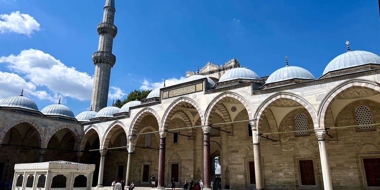 Dziedziniec meczetu süleymaniye w stambule z minaretem i kopułami pod błękitnym niebem