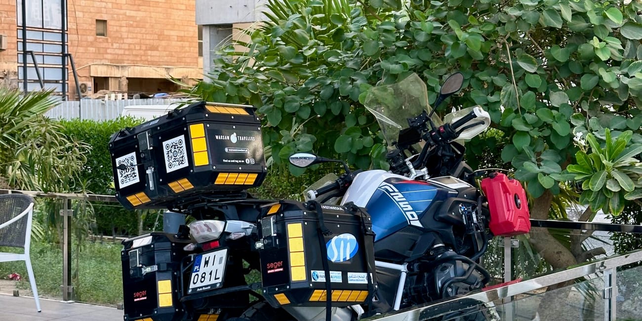 Kuwait motorcycle parked near hotel entrance, with side boxes and a protective barrier display