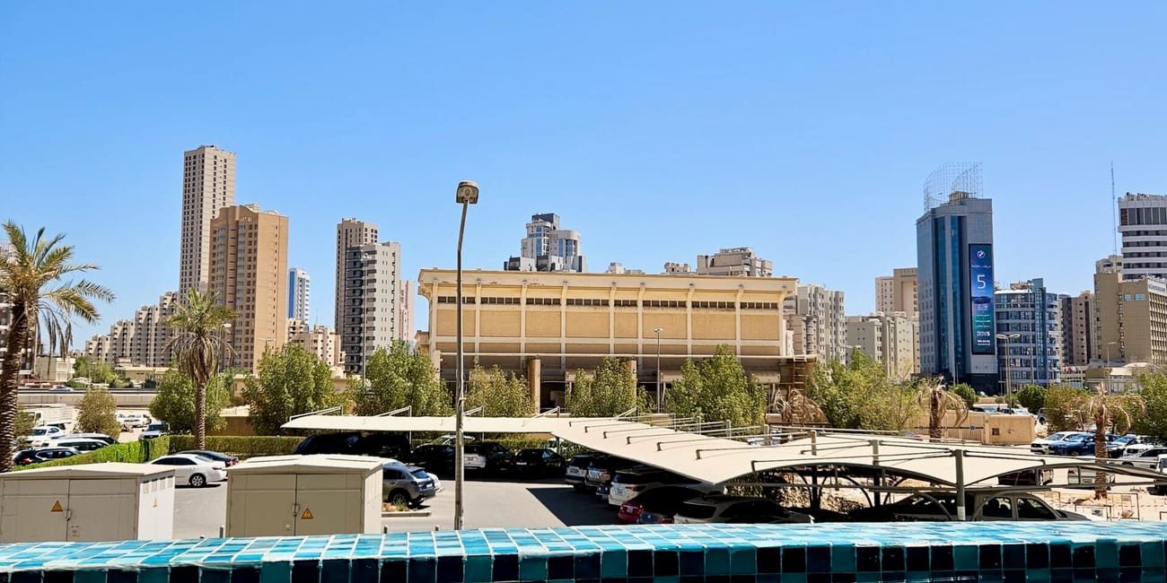 Kuwait, view from hotel’s pool overlooking a city skyline from a blue swimming pool