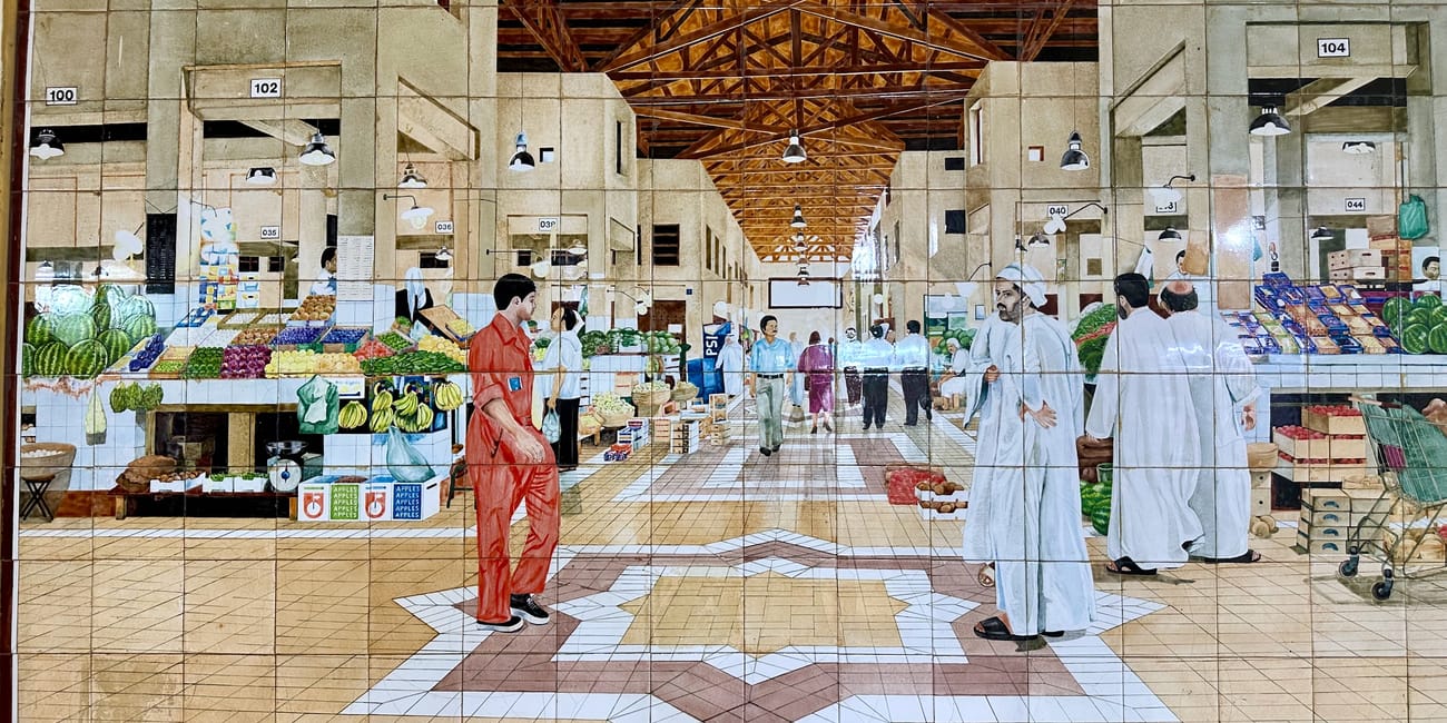 Kuwait, city al mubarakiya indoor market scene with shops, fruit displays, and shoppers walking through.
