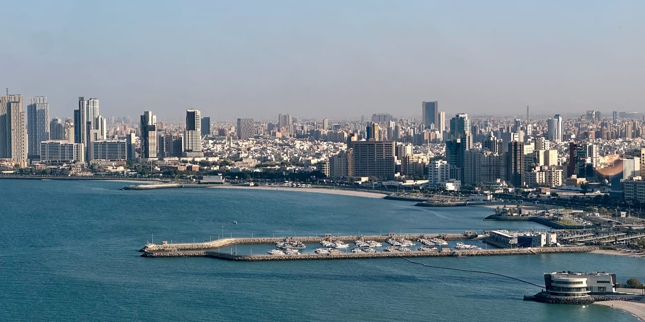 Kuwait city towers skyline along the waterfront with modern high-rise buildings and marina.